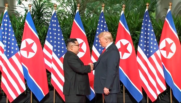 North Korean leader Kim Jong Un (left) and U.S. President Donald Trump on June 12, 2018, shake hands before holding their summit in Singapore. (Yonhap News)